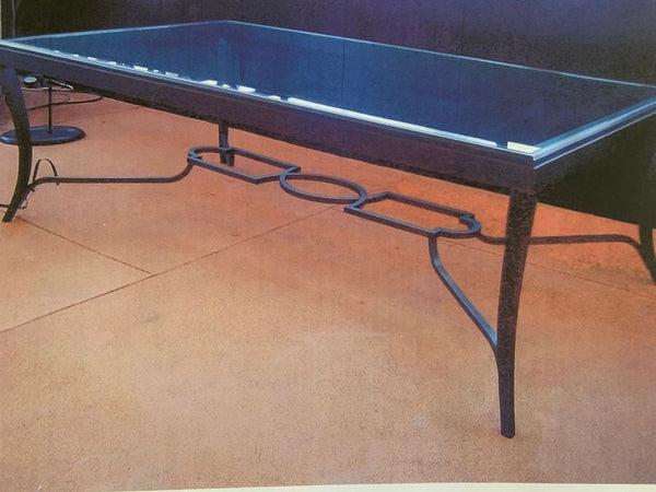 1. Rectangular glass coffee table with decorative black metal frame by Carole Gratale Inc., seen outdoors.  