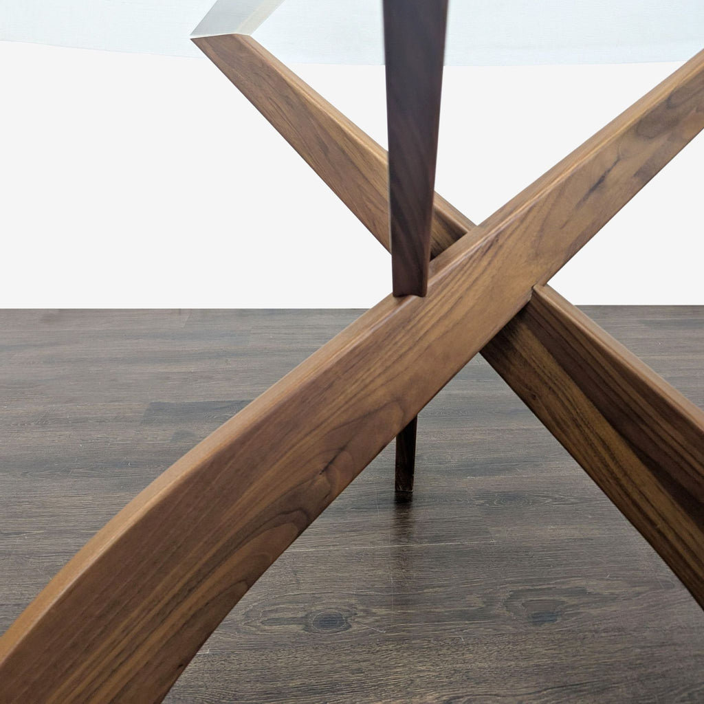 3. Detail view of intersecting wooden legs supporting a round glass dining table.