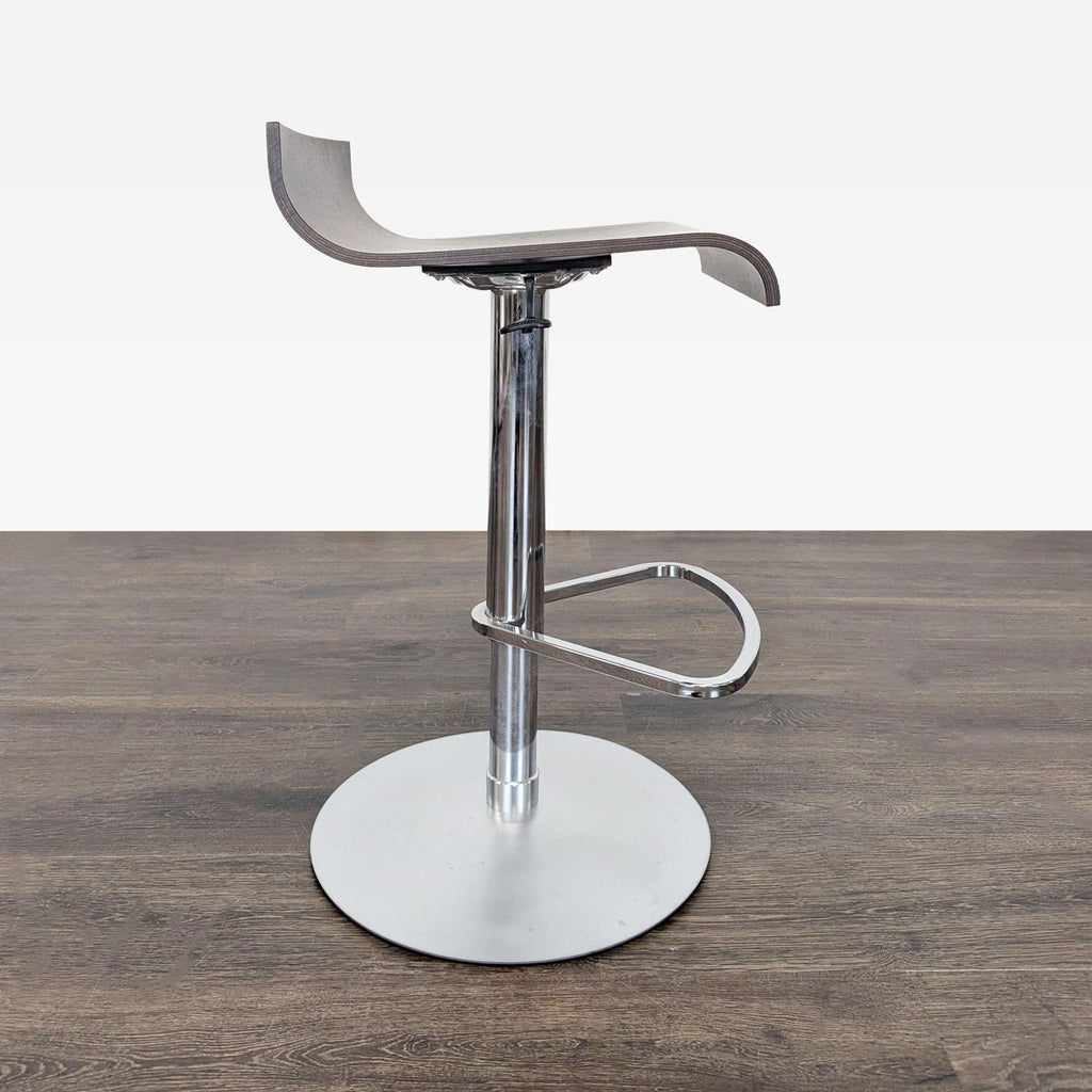2. Side view of a modern walnut Ligne Roset Pam bar stool with curved seat and chrome hydraulic base.  