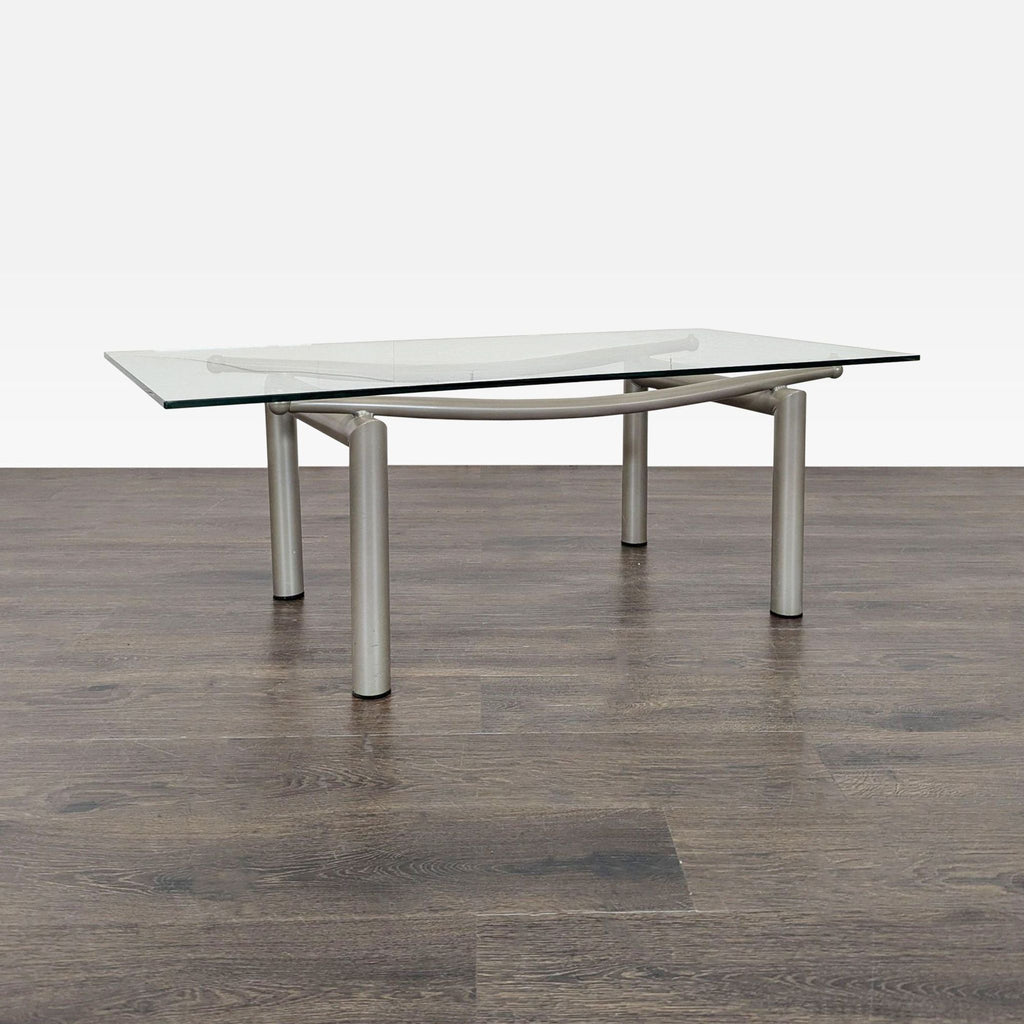 2. Sleek coffee table featuring a clear glass top supported by curved silver metal frame and legs.