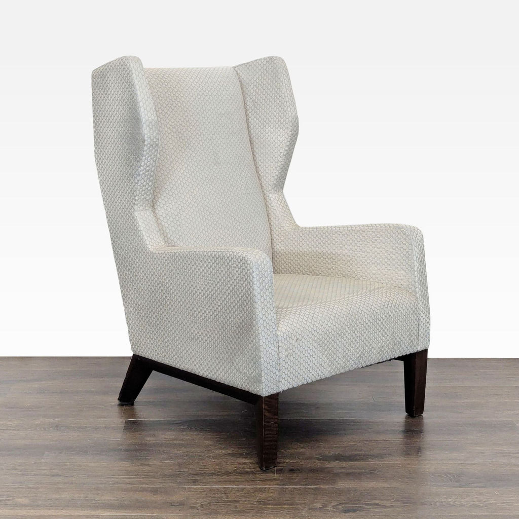 Angled side view of a Holly Hunt lounge chair, showcasing its wingback design and elegant cream upholstery.  