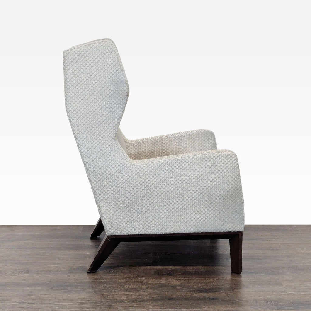 Profile shot of a Holly Hunt lounge chair, displaying its clean lines, textured fabric, and sturdy dark wood base.