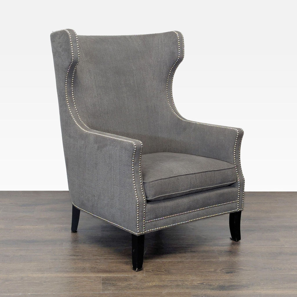 2. Angled view of a modern gray Bernhardt lounge chair with nailhead accents and black legs on wood floor.  