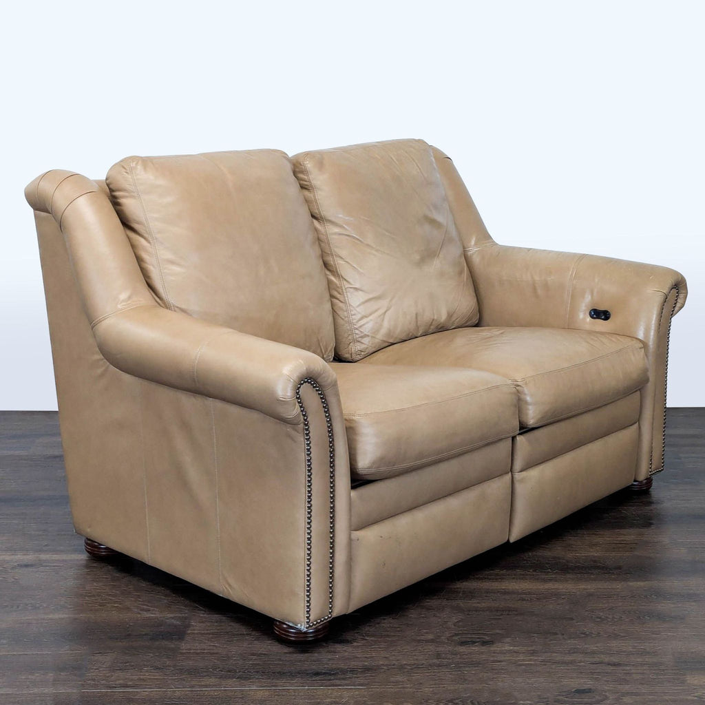 Cozy Bradington-Young loveseat featuring nailhead trim and two reclining seats, upholstered in tan leather.
