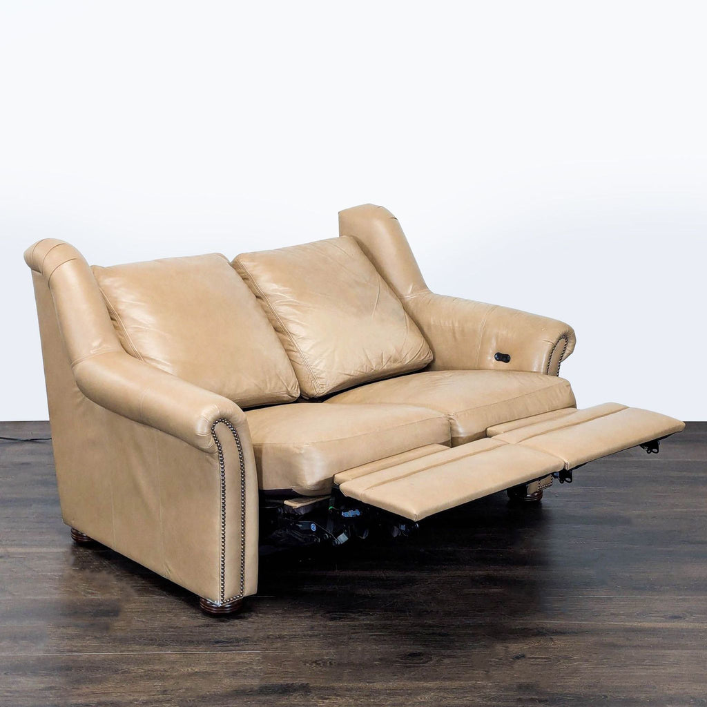 Tan leather Bradington-Young loveseat with classic nailhead accents and built-in recliners on both sides.