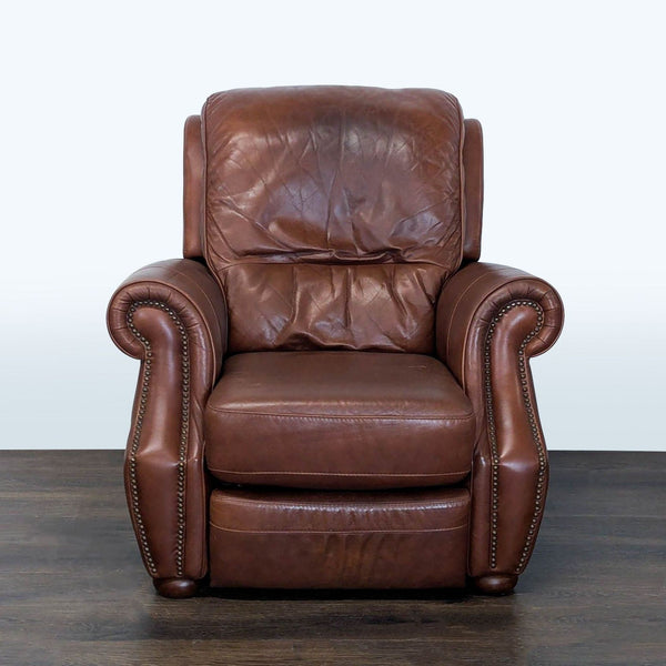 Brown leather recliner with nailhead trim, padded armrests, and a plush backrest for lounge relaxation.