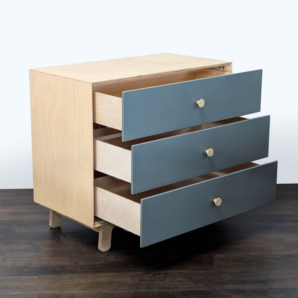 Stylish blue and wood Ouef dresser featuring three spacious drawers, ideal for bedroom or nursery storage.  
