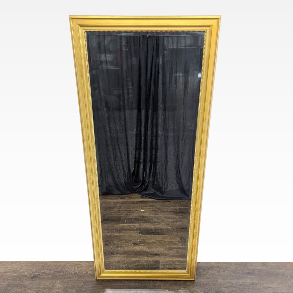 Gold-framed floor mirror standing upright, reflecting a minimalistic modern space.