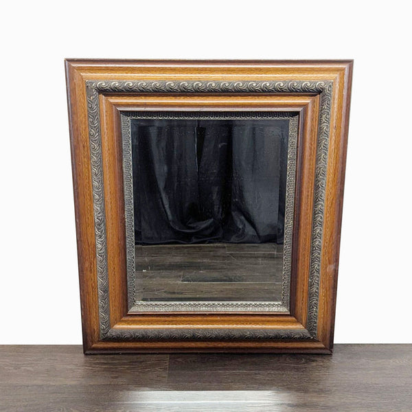 1. Rectangular framed mirror with ornate wood and metal detailing, leaning against a dark wood floor background.
