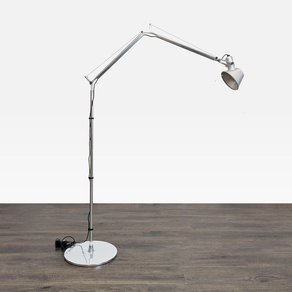 Artemide silver floor lamp with adjustable arm and pivoting head, ideal for modern living spaces.