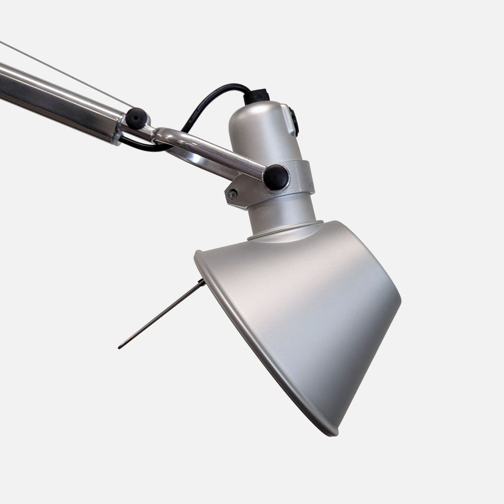 Sleek silver Artemide floor lamp featuring a round base, movable head, and minimalist design.