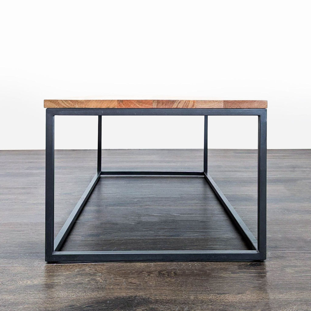 3. Side view of West Elm coffee table with industrial design, wooden top, and blackened steel open base.
