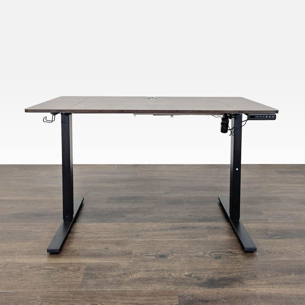 Modern electric standing desk with dark wood top, black metal legs, and electronic height controls.  