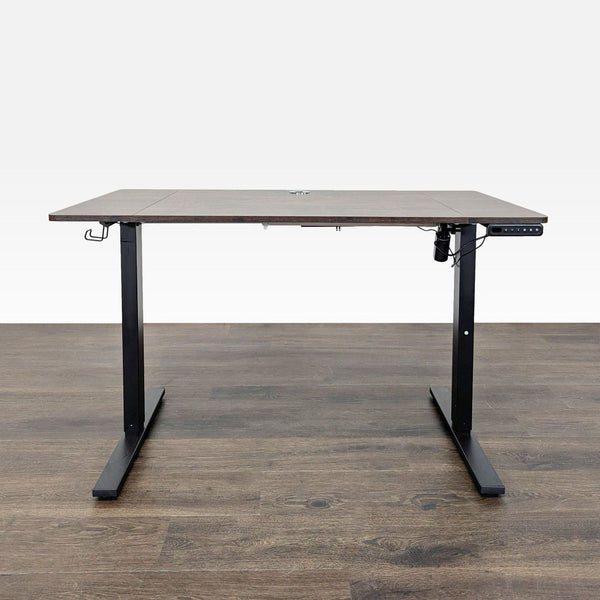 Modern electric standing desk with dark wood top, black metal legs, and electronic height controls.  