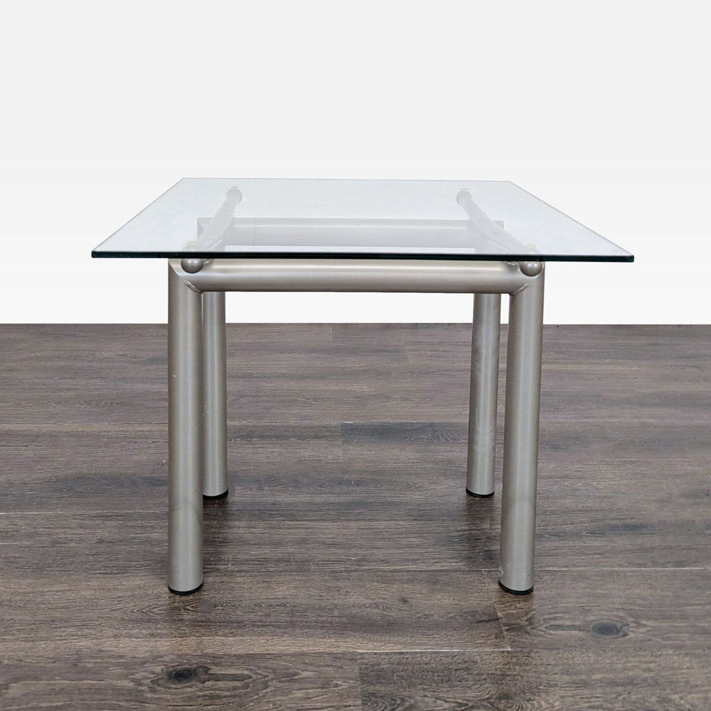 1. Modern Roy & Bénot end table with clear glass top and metal cylindrical legs, shown on a wooden floor.
