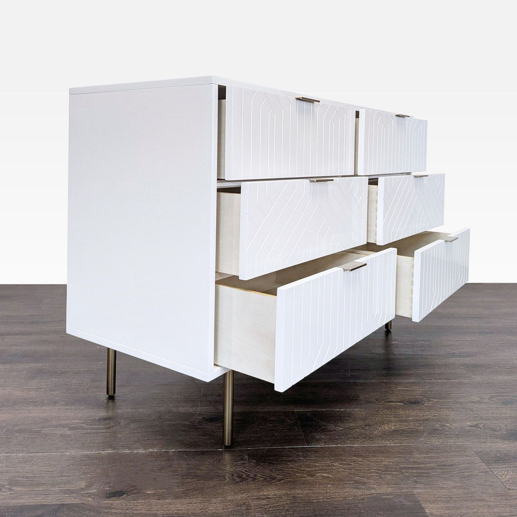 Modern white dresser by Pottery Barn, featuring sleek brass handles and spacious storage; top shows some wear.  