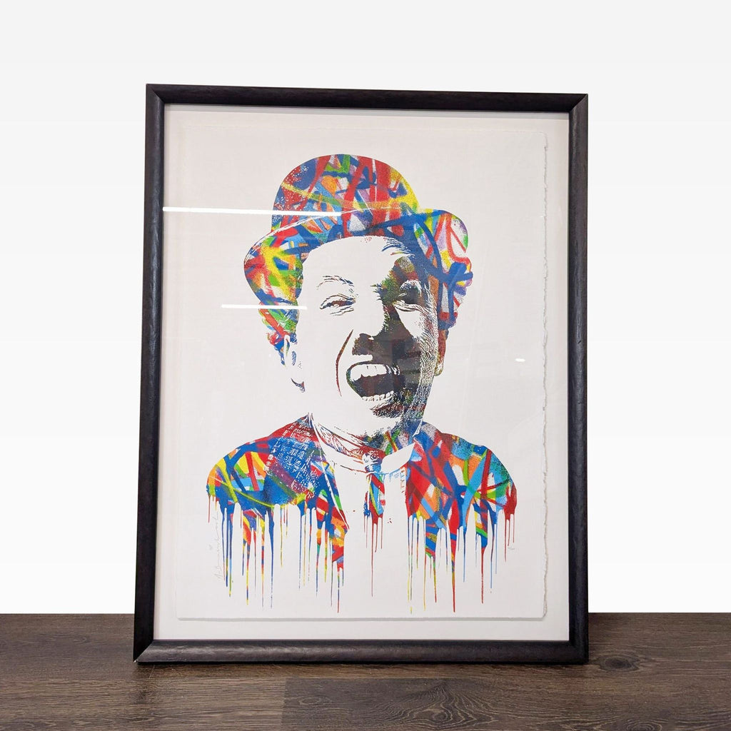 Colorful portrait artwork by Mr. Brainwash with dynamic splashes, signed and framed in sleek black, ready to hang.