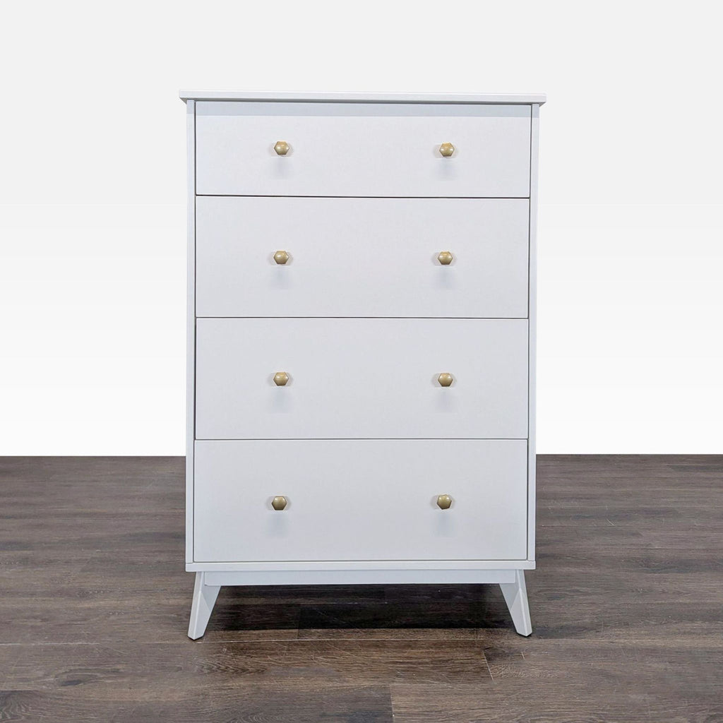 Front view of a Pottery Barn Teen white dresser with four drawers and gold knobs on a wood floor.
