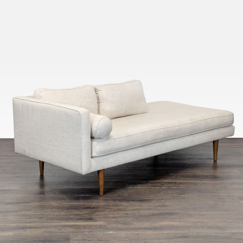 Light beige chaise sofa by West Elm, featuring clean lines, back cushions, and a matching bolster pillow.
