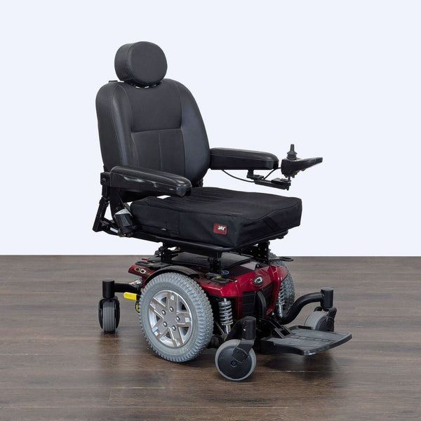 Quantum power wheelchair with wide black leather seat, red frame, large wheels, and joystick controller.