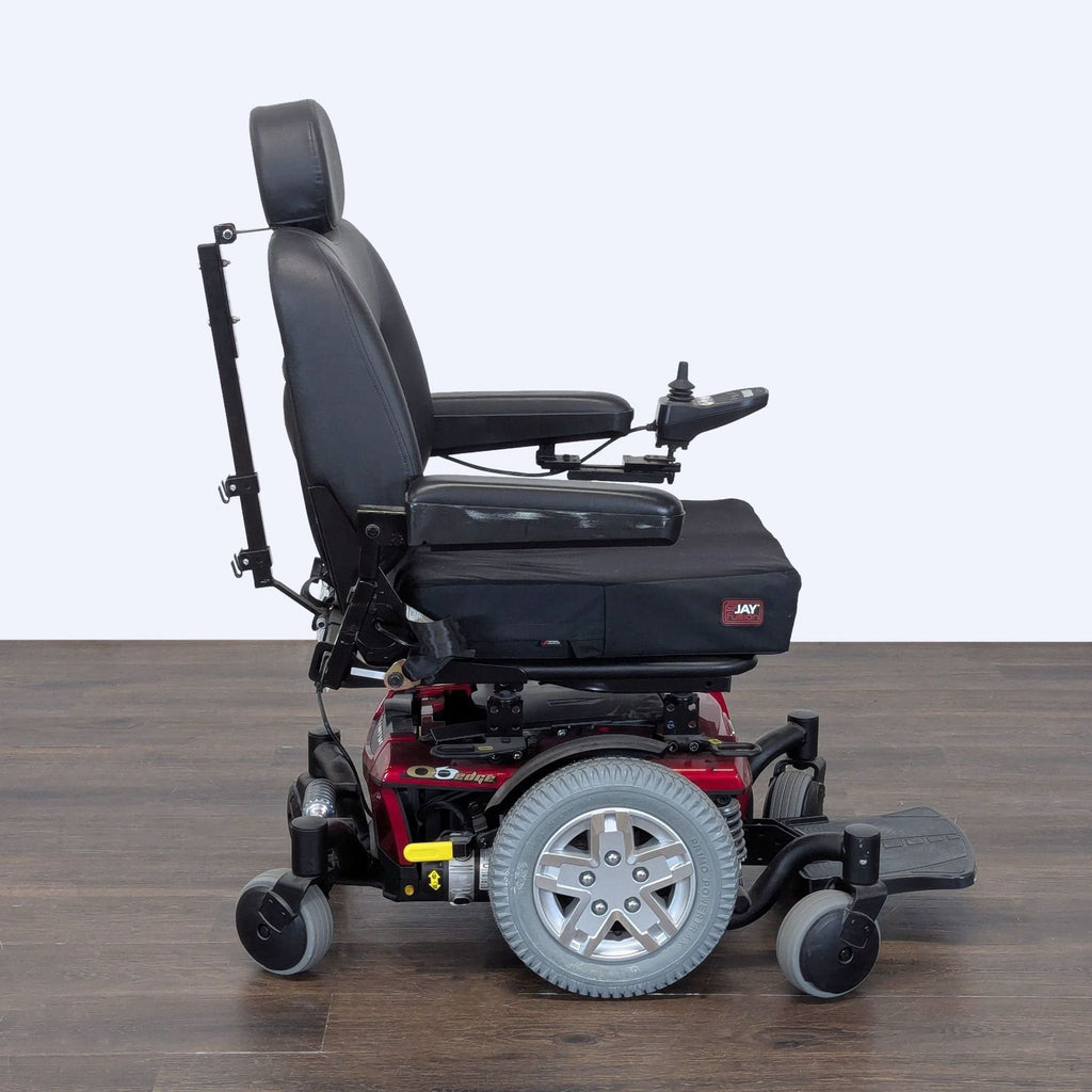 Red Quantum power wheelchair featuring cushioned armrests, adjustable headrest, and sturdy construction.