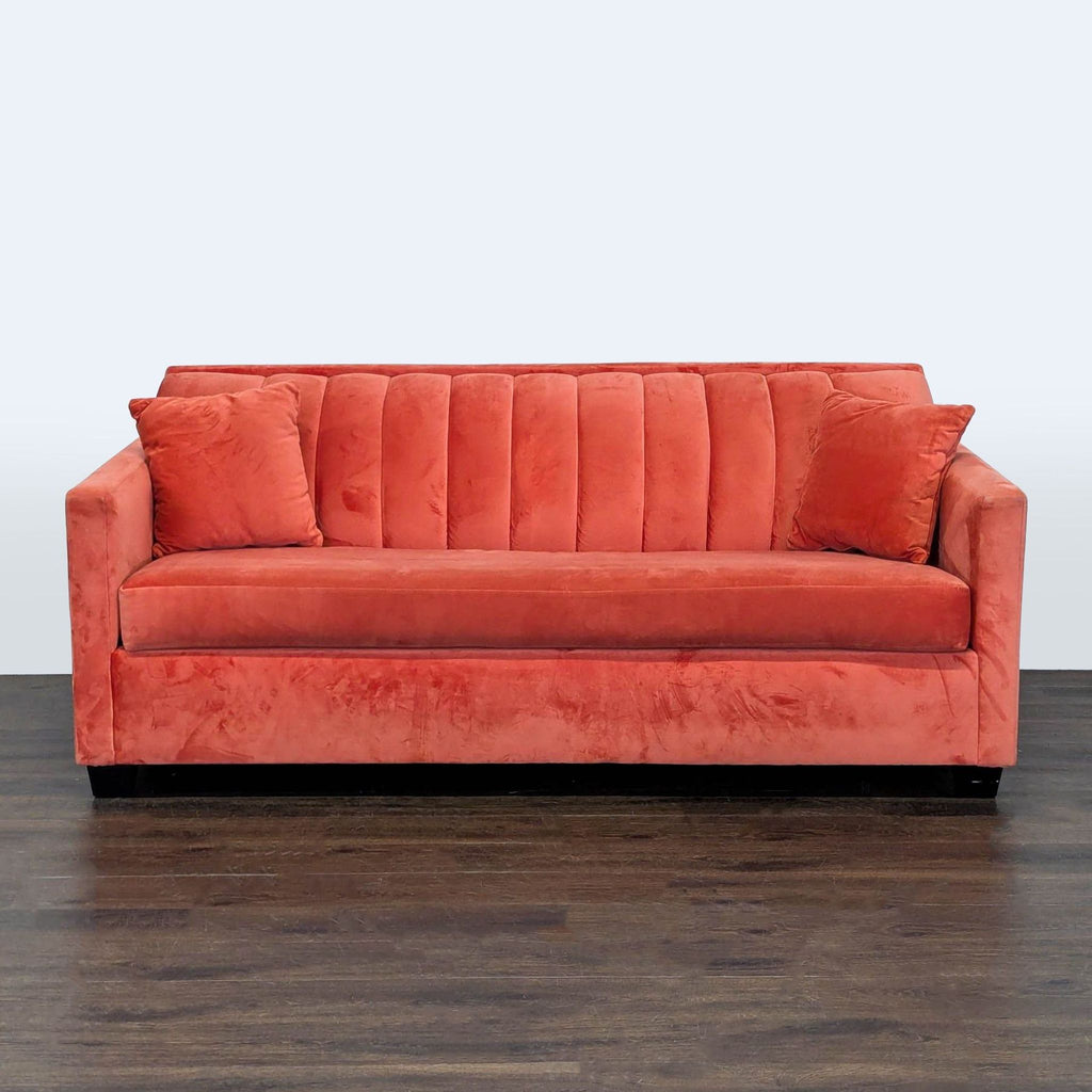 Modern coral velvet sleeper sofa with clean lines, plush cushions, and two matching pillows in a living room.