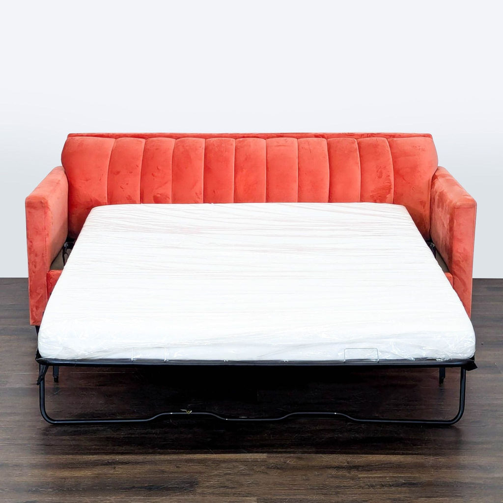 Contemporary sleeper sofa in coral velvet, featuring soft upholstery and sturdy design, includes two accent pillows.