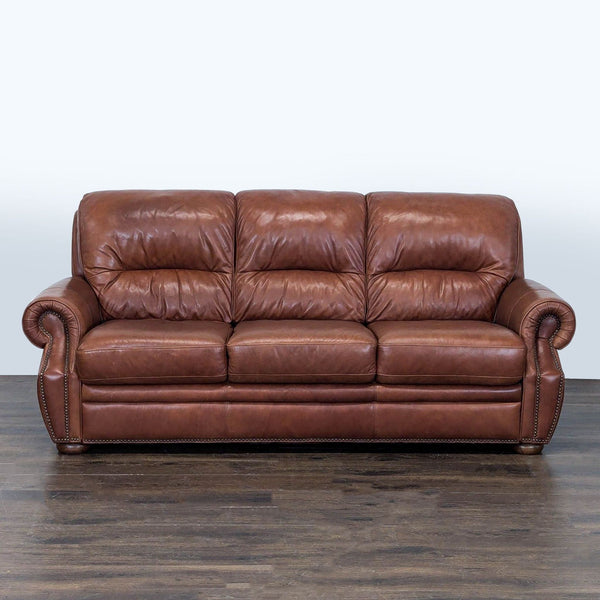 Brown leather 3-seat sofa with rolled arms, nailhead trim, and plush cushioning for living room comfort.