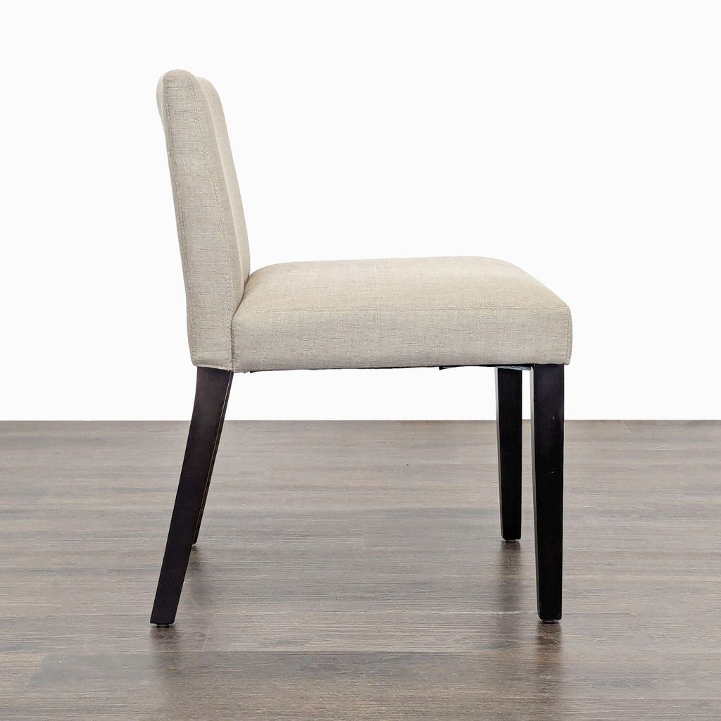 3. Side profile of EQ3 Mid-Century style dining chair with beige fabric and wood legs.