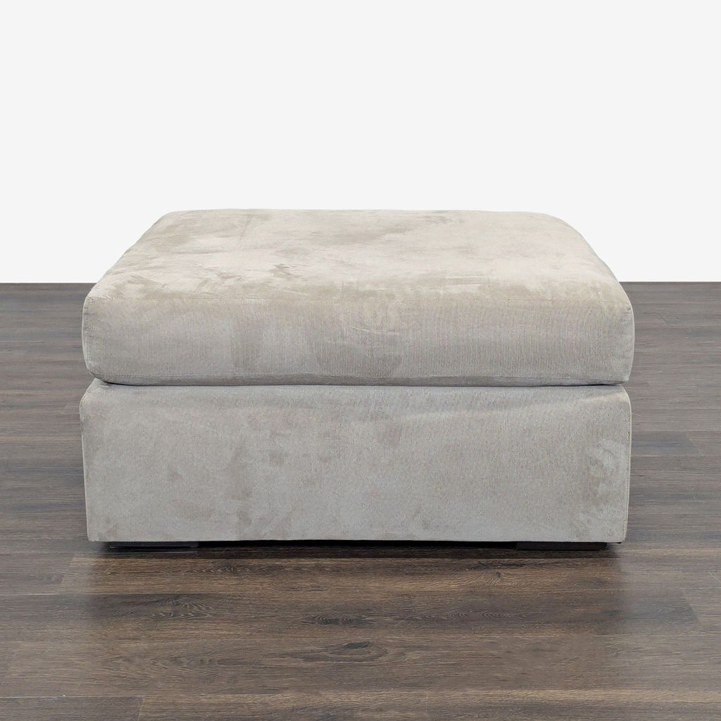 1. Light grey square ottoman with plush top, shown on a dark wooden floor, front view.