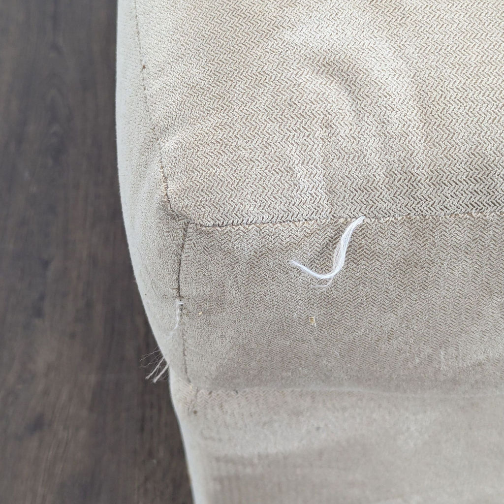 3. Close-up showing corner fabric detail of the ottoman with visible stitching and a loose thread.