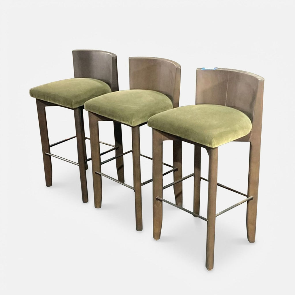 Three handcrafted Delancey stools from Maiden Home featuring ash wood, olive green seats, and a sturdy metal footrest.  