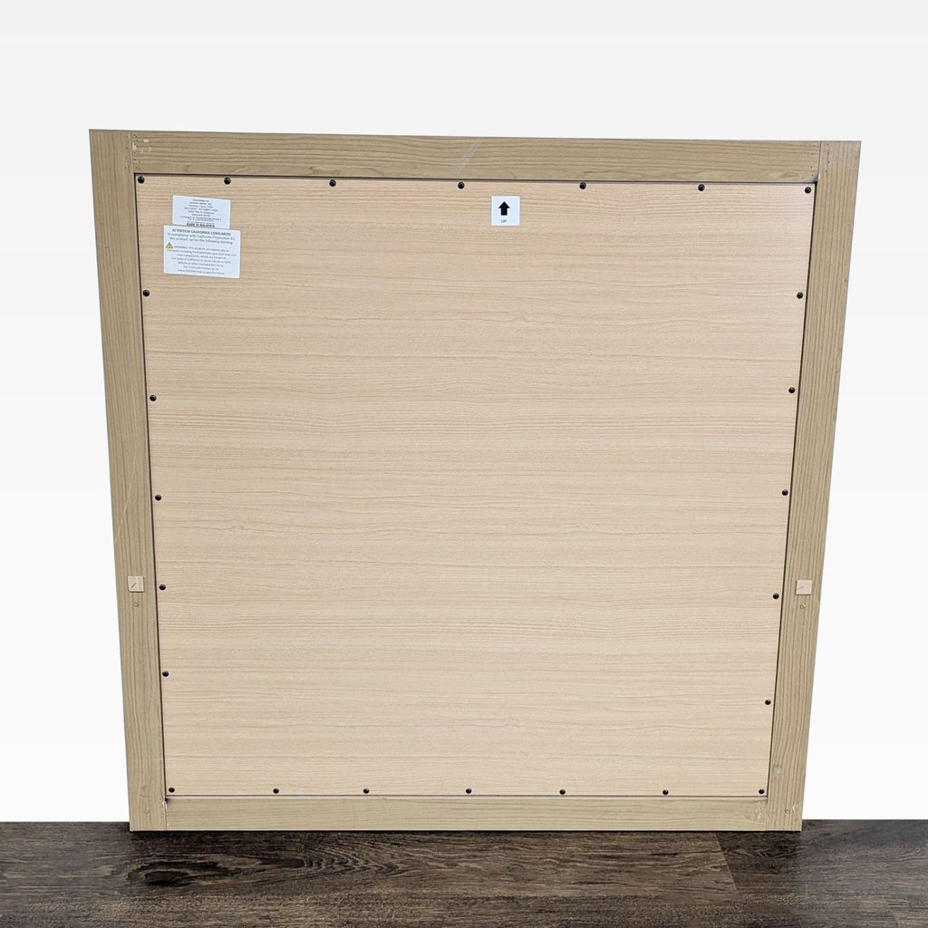 2. Back view of the Crown Mark mirror showing a light wood panel with hardware and attached brand labels.