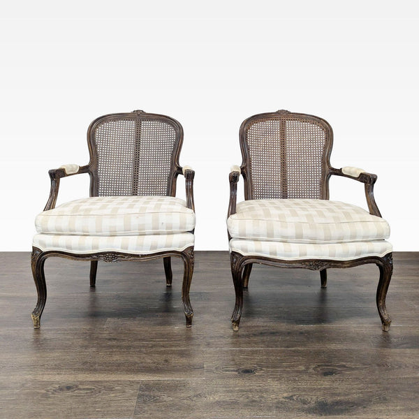 Pair of vintage-inspired lounge chairs with wooden frames, cane backs, and striped cushioned seats.