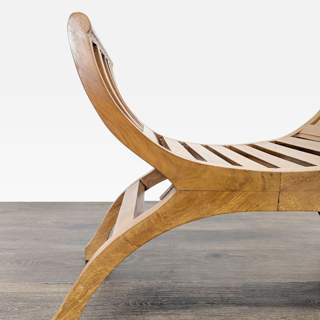 Curved wooden bench with slatted seat and backrest, shown from a side angle on a wood floor.