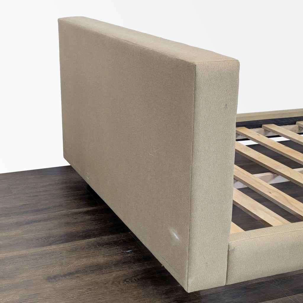 3. Close-up of the side of a beige upholstered bed frame headboard, displaying sturdy fabric texture and support slats.