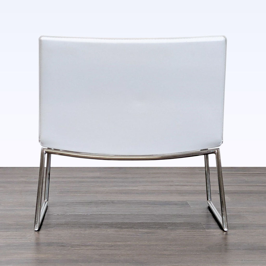 Minimalist CB2 lounge chair with a white cushion and shiny chrome base, perfect for versatile lounge decor.