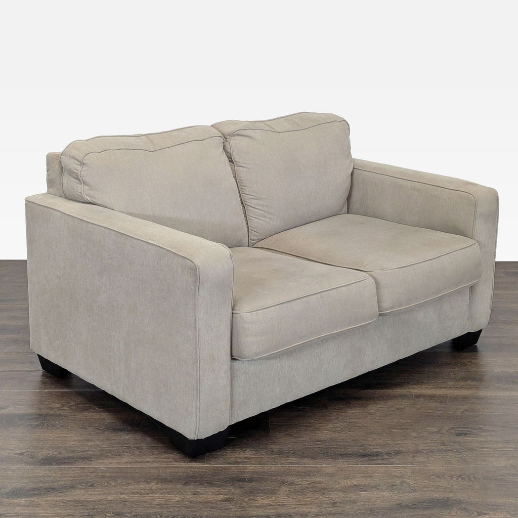 2. Modern Ashley loveseat in beige with clean lines, plush cushions, and sturdy arms, ideal for small spaces.