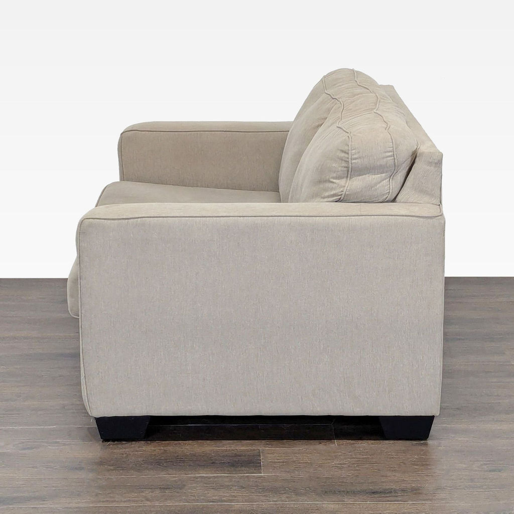 3. Side view of a beige Ashley Furniture loveseat showing thick armrests, plush cushions, and wooden legs.