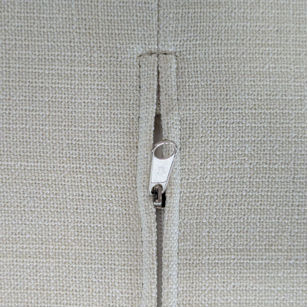 3. Closeup of a beige textured cushion cover with a metal zipper, showing the removable cover feature.