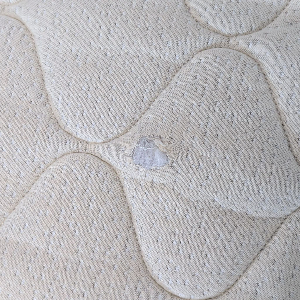 3. Close-up of sleeper sofa mattress fabric showing a visible tear or hole in the surface material.