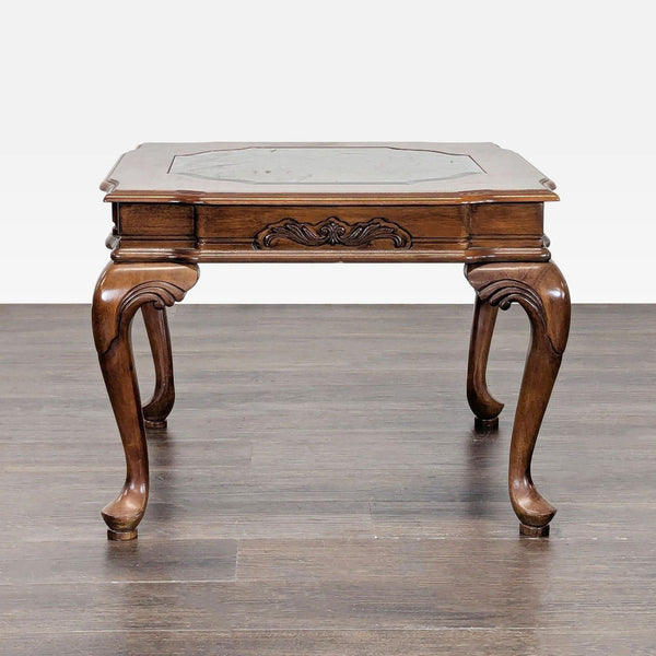 Ornate end table with carved cabriole legs and a glass insert on the tabletop.