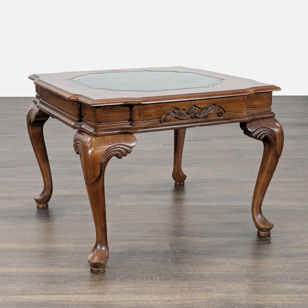 Antique-style end table with detailed legs and a glass panel set into the surface.