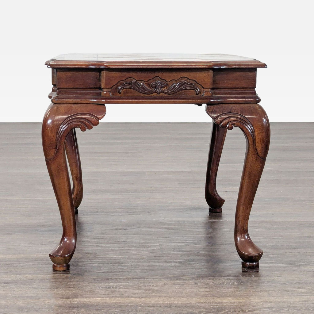 Carved wooden table featuring ornate cabriole legs and an inlaid decorative tabletop.  