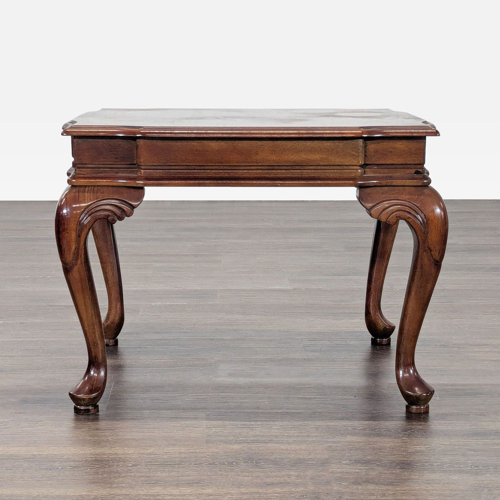 Elegant table with intricately carved legs and a patterned inlaid top surface.  