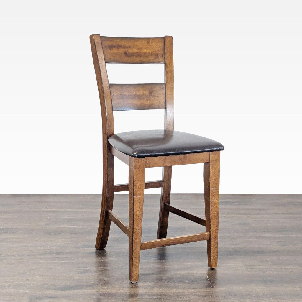 Angled view of a wooden stool featuring a ladder-back style and cushioned brown seat, placed indoors.