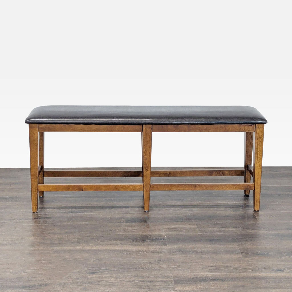 2. Front view of a long wooden bench with a padded black seat in the Stools, Ottomans & Benches category.