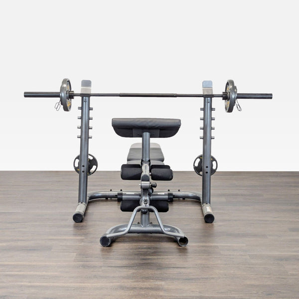 Gold's Gym weight bench with barbell and plates, featuring padded supports for home strength training.