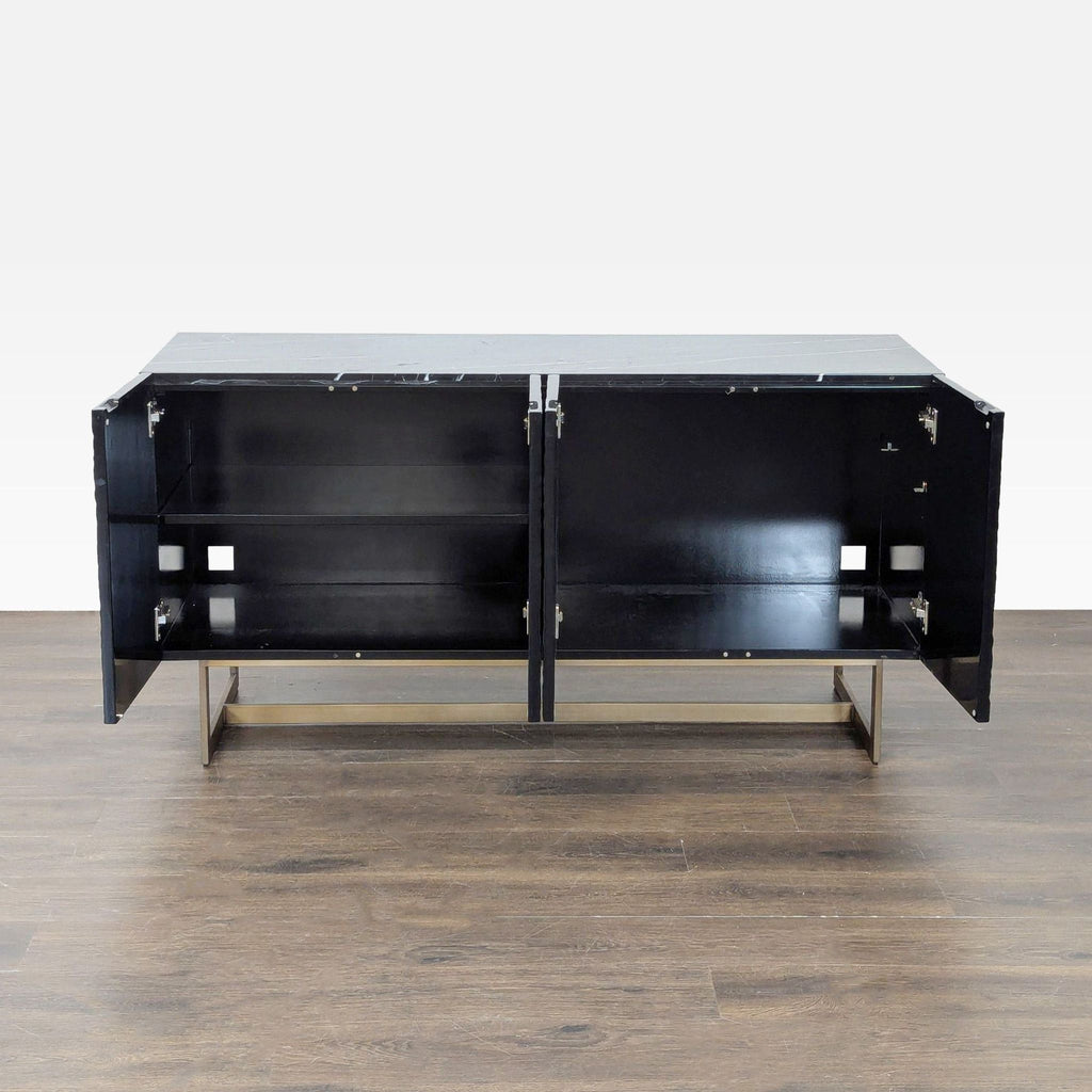 Modern black CB2 sideboard featuring brass-finished metal legs and spacious interior shelving behind four doors.