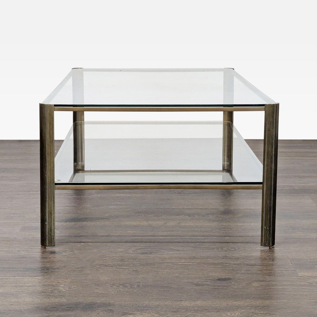 3. Side view of a glass coffee table with a metal frame and two clear shelves on wooden flooring.